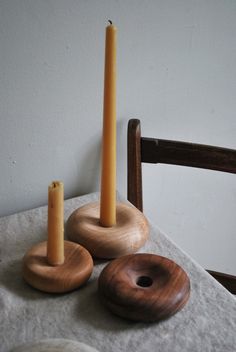 three candles are sitting on a table next to donuts and a wooden candle holder