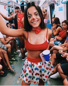 a woman in a red top and polka dot skirt on a train with other people