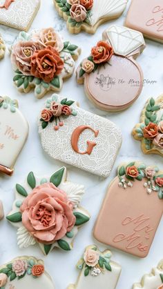 decorated cookies are arranged on a table with name tags and flowers in the middle one cookie has a monogram