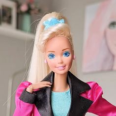 a barbie doll with blonde hair and blue eyes wearing a pink dress, black jacket and turquoise shoes