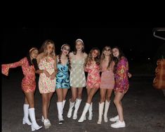 a group of young women standing next to each other in front of a car at night