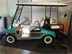 a blue golf cart parked in a room next to a wall with pictures on it