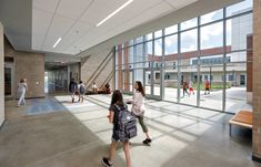 several people walking in an empty building with large windows