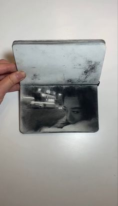 a person holding up an old photo in their left hand