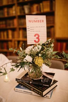 a vase filled with white flowers sitting on top of a table next to two books