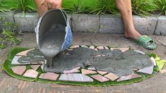 a person is pouring cement into a potted planter on the ground with green plants in the background