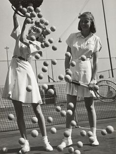 two women holding tennis rackets and balls in the air