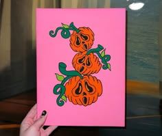 a person holding up a pink card with pumpkins on it