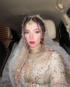 a woman in a car wearing a bridal gown and head piece with beads on it