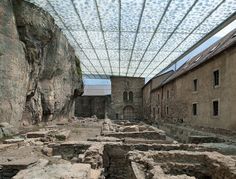 an old building that is in the middle of some rocks and has a glass roof over it