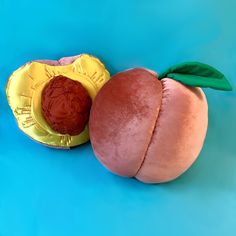 an apple and a piece of fruit on a blue surface with one peach cut in half