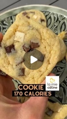 someone holding a cookie in their hand with chocolate chips on the top and white crumbs on the bottom