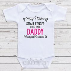 "Cute One-Piece Bodysuits For Babies - I May Have A Small Finger But I Have Daddy Wrapped Around It - Bodysuits for Girls. Great For Baby Shower Gifts, Newborn Clothing, Baby Clothes or 1st birthdays. Short And Long Sleeve Bodysuits Available. Each of our cute bodysuits for babies are professionally heat pressed using a high-quality transfer (NOT iron-on like some vendors use) and the design is embedded in the shirt so that it is machine washable and dryer friendly. It's advised to launder insid Funny Fitted Onesie For Gender Reveal, Fitted Funny Onesie For Gender Reveal, Fitted Onesie With Letter Print For Gender Reveal, Fitted Onesie With Letter Print For First Birthday, Fitted Letter Print Onesie For First Birthday, First Birthday Fitted Bodysuit With Letter Print, Fitted Onesie For First Birthday, First Birthday Bodysuit With Letter Print, Fitted Bodysuit With Name Print For First Birthday