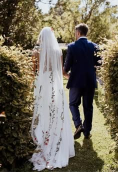 a bride and groom walking through the bushes