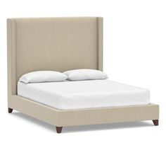 an upholstered bed with white sheets and pillows