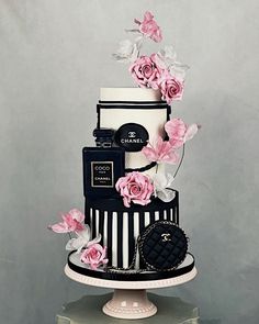 a three tiered black and white cake with pink flowers on top is decorated with chanel