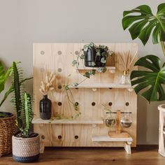 a wooden shelf with potted plants on it next to two wicker baskets filled with houseplants