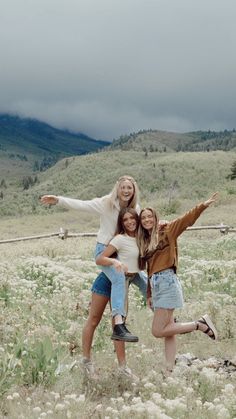 three girls are posing for the camera in a field