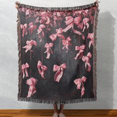 a woman standing in front of a wall holding up a pink and black floral tapestry