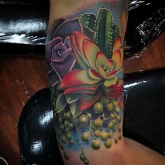 a woman's leg with a colorful flower and succulents on it