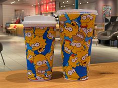 two cups with the simpsons characters on them sitting on a table in an office building