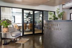 the entrance to an office building with glass doors and potted plants on the desk