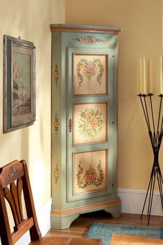 an ornate armoire in the corner of a room with candles and pictures on the wall