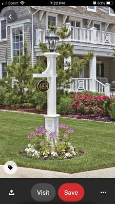 a white lamp post sitting in the middle of a yard next to flowers and trees