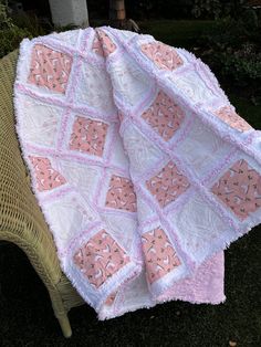 a pink and white quilt sitting on top of a chair next to a wicker chair