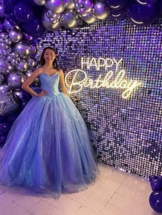 a woman in a blue dress standing next to balloons and the words happy birthday written on it