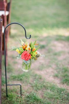 a bouquet of flowers is hanging from the back of a pew at a wedding ceremony