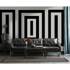 a living room with black and white stripes on the wall, leather couches and rugs