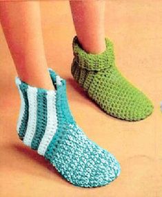 a person wearing green and white crocheted slippers