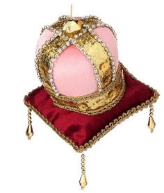 a pink and gold crown sitting on top of a red pillow