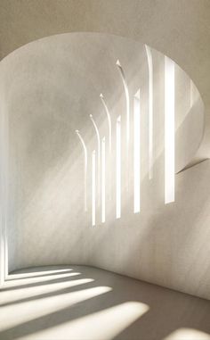 sunlight streams through the windows in an empty room with white walls and concrete flooring