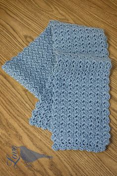 two crocheted blue napkins sitting on top of a wooden table