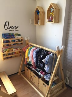 a child's clothing rack with clothes on it in a room next to a wall