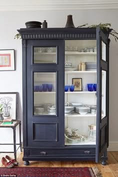 an old china cabinet with glass doors and shelves filled with dishes, plates and glasses