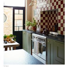 a kitchen with green cabinets and an oven in the center, next to a window