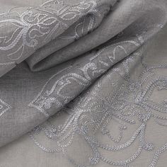 a close up view of an embroidered fabric with silver thread and beads on the side