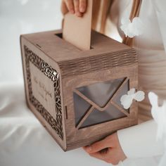 a person holding a wooden box with an envelope inside