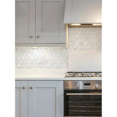 a stove top oven sitting inside of a kitchen next to white cupboards and counter tops