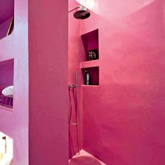 a bathroom with pink walls and shelves on the wall