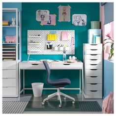 a white desk and chair in front of a blue wall with pictures on the wall