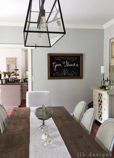 a dining room table with white chairs and a chalkboard on the wall above it