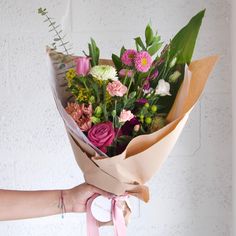 a woman holding a bouquet of flowers in her hand with a tag on the end