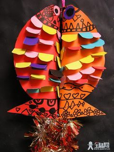 an owl made out of colored paper sitting on top of tinsel