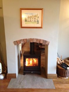 a wood burning stove sitting inside of a living room next to a wall mounted painting