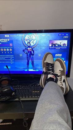 a person's feet resting on a desk in front of a computer monitor and keyboard