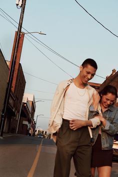 two people walking down the street with one holding his arm around the other's shoulder